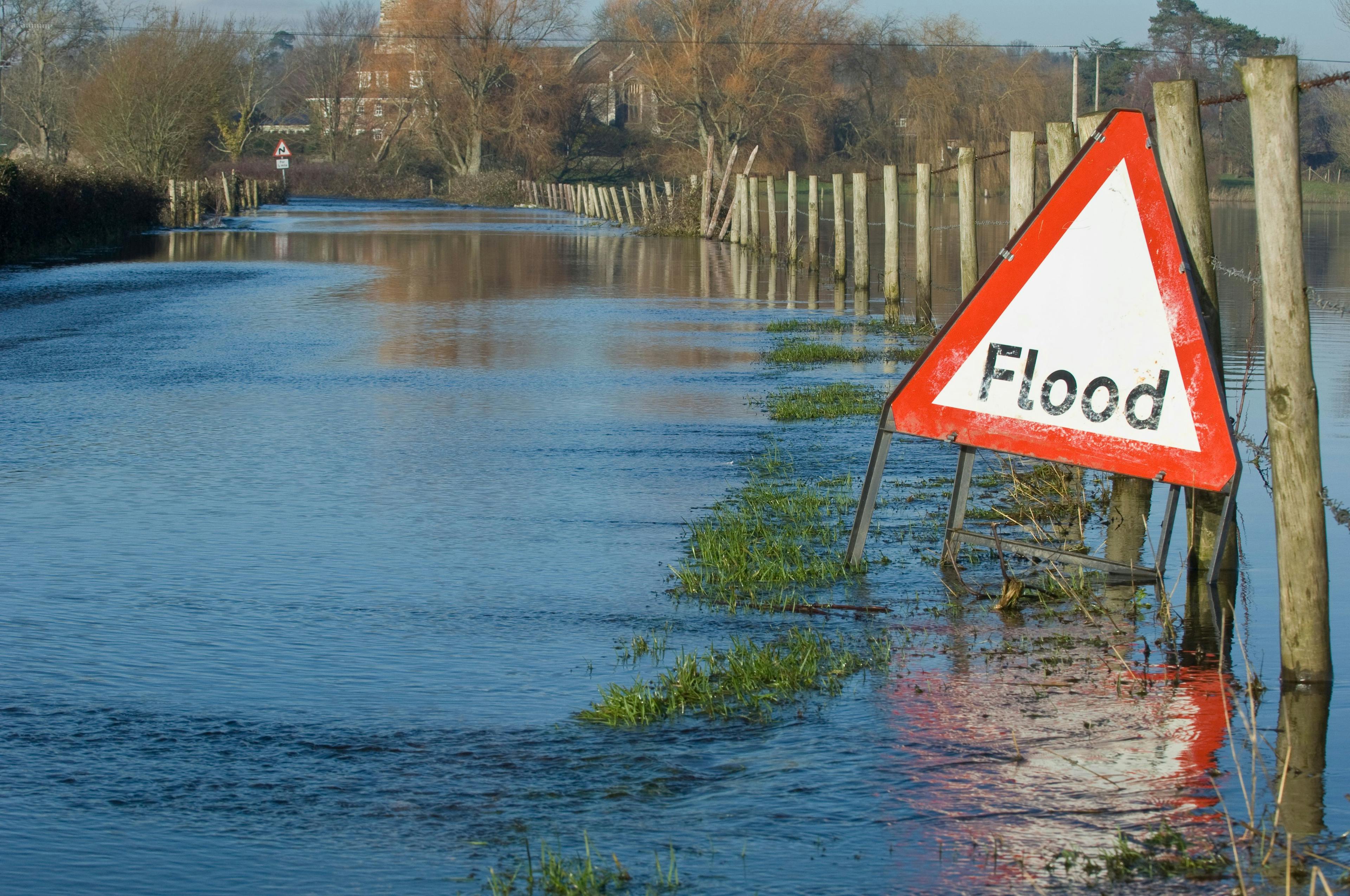 A warning sign that says flood marking a flooded street 